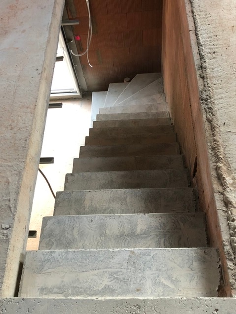 Escalier beton brut de décoffrage le long d'un mur en brique.