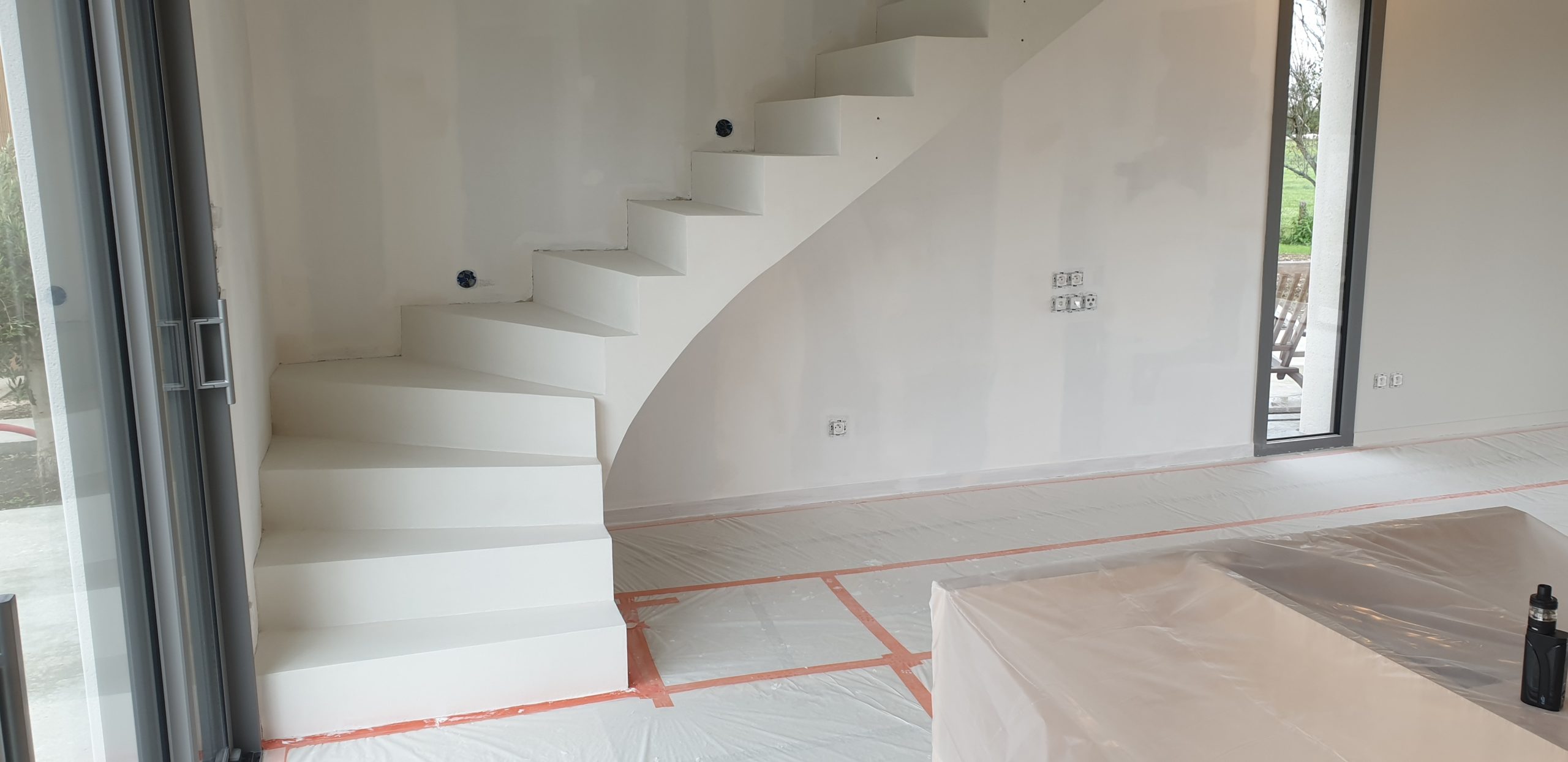 Escalier coulé en béton brut puis revêtement en béton ciré blanc dans une maison en construction