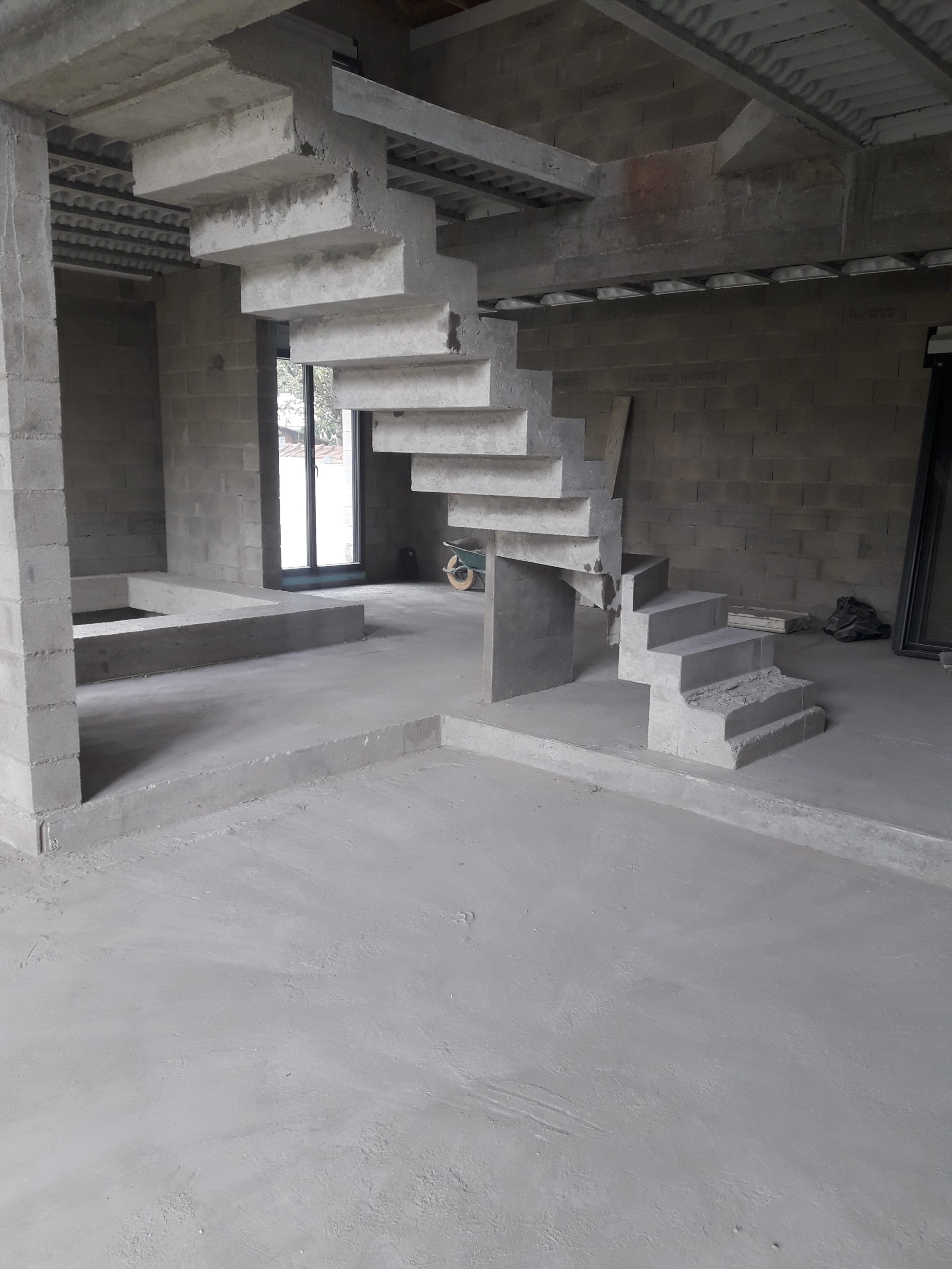 Escalier béton design tournant dans une maison en construction