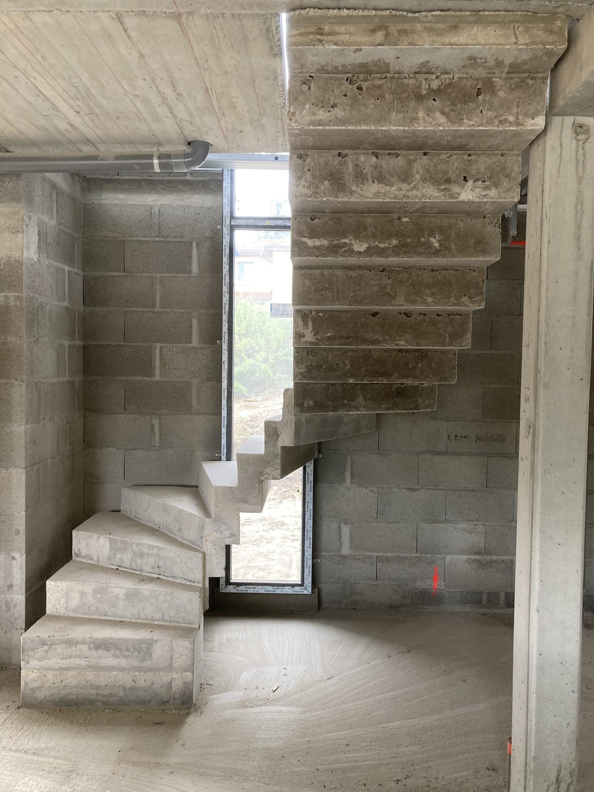Escalier béton devant une baie vitrée dans une maison individuelle