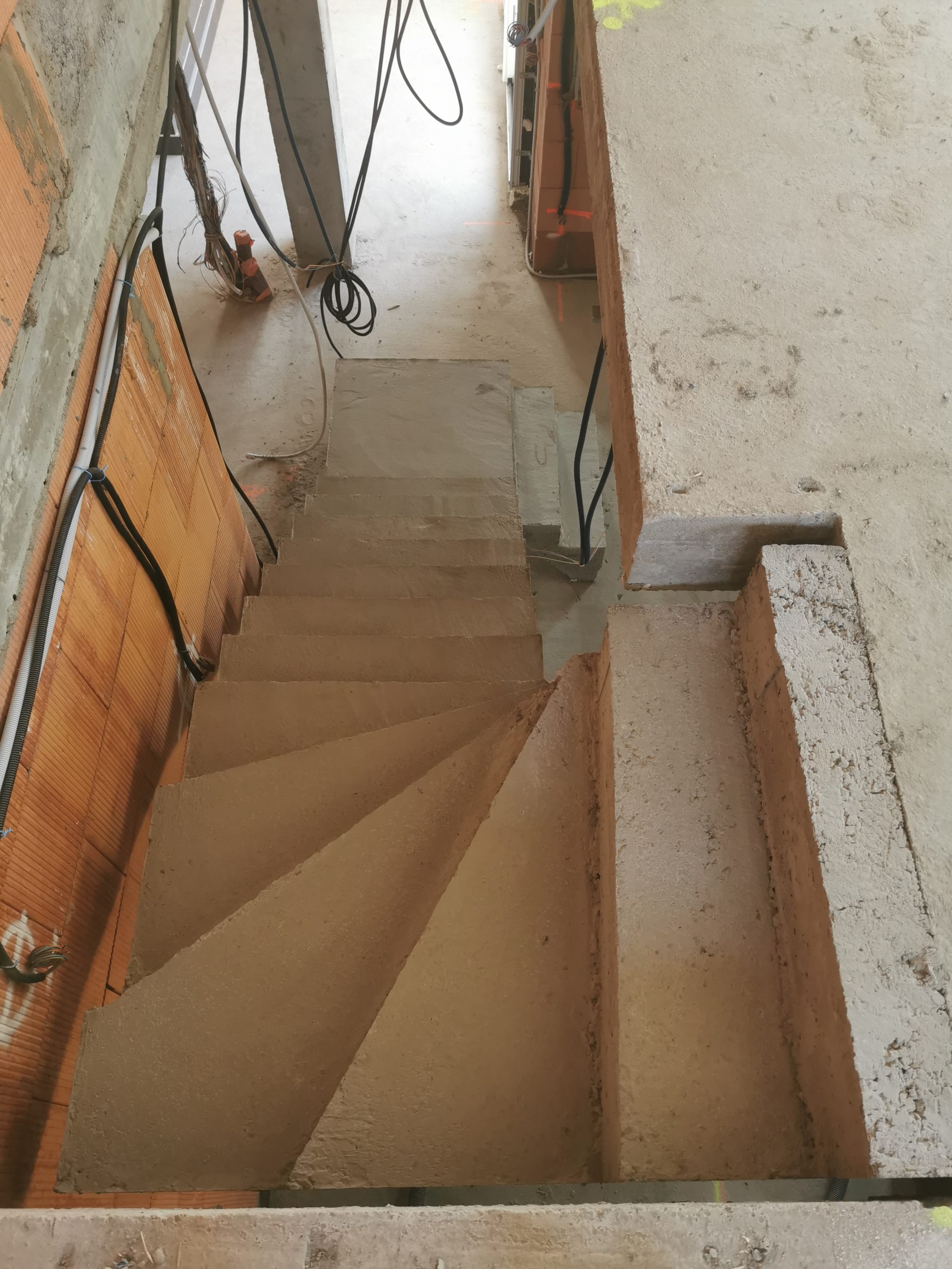 Vue de dessous d'un escalier décoffré dans une maison en construction.