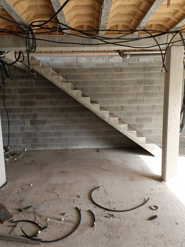 Montée d'un escalier béton à paillasse le long d'un mur, dans une maison près de Toulouse, en région Occitanie.