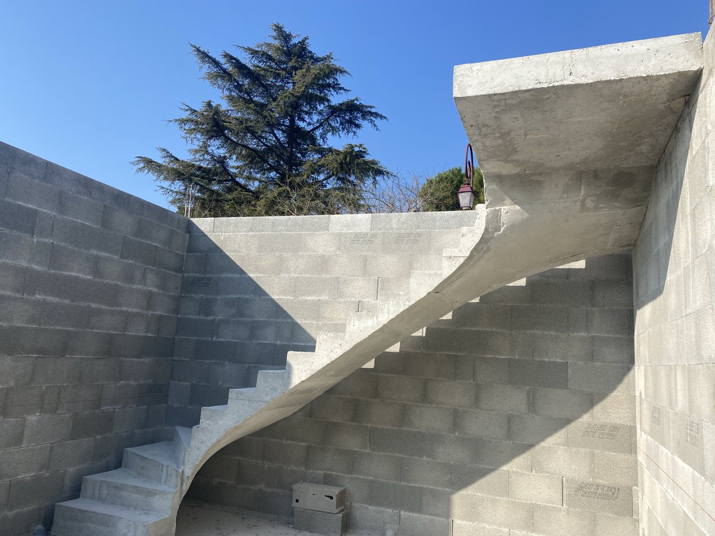 Escalier à paillasse deux quart tournant, avec palier. Structure architecturale en béton brut de décoffrage, dans une maison située à Pont-Saint-Esprit près de Pierrelatte et Saint-Paul-Trois-Châteaux.