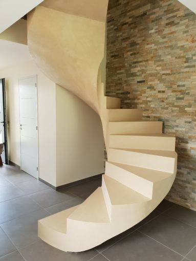 Escalier hélicoïdal en béton ciré, en vernis mat, couleur beige, et lumière centrale, pensé et conçu sur site dans les Hauts-de-France.