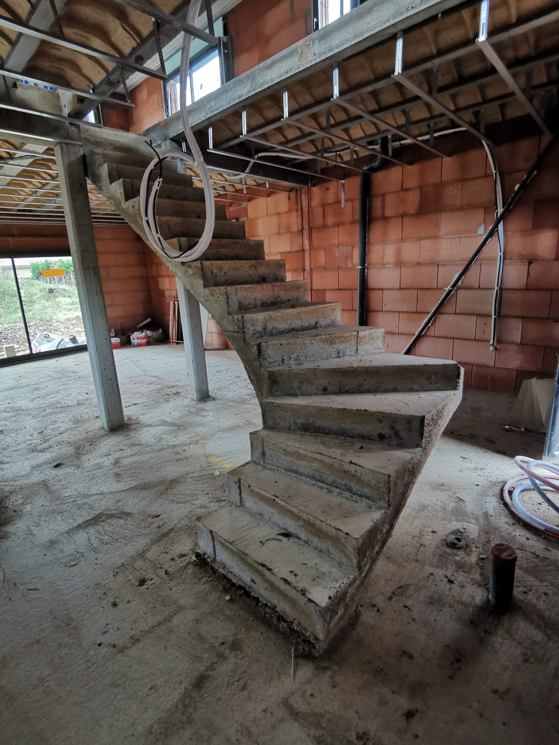 Départ de l'escalier en quart tournant à gauche pour accéder à l'étage de cette maison individuelle en construction