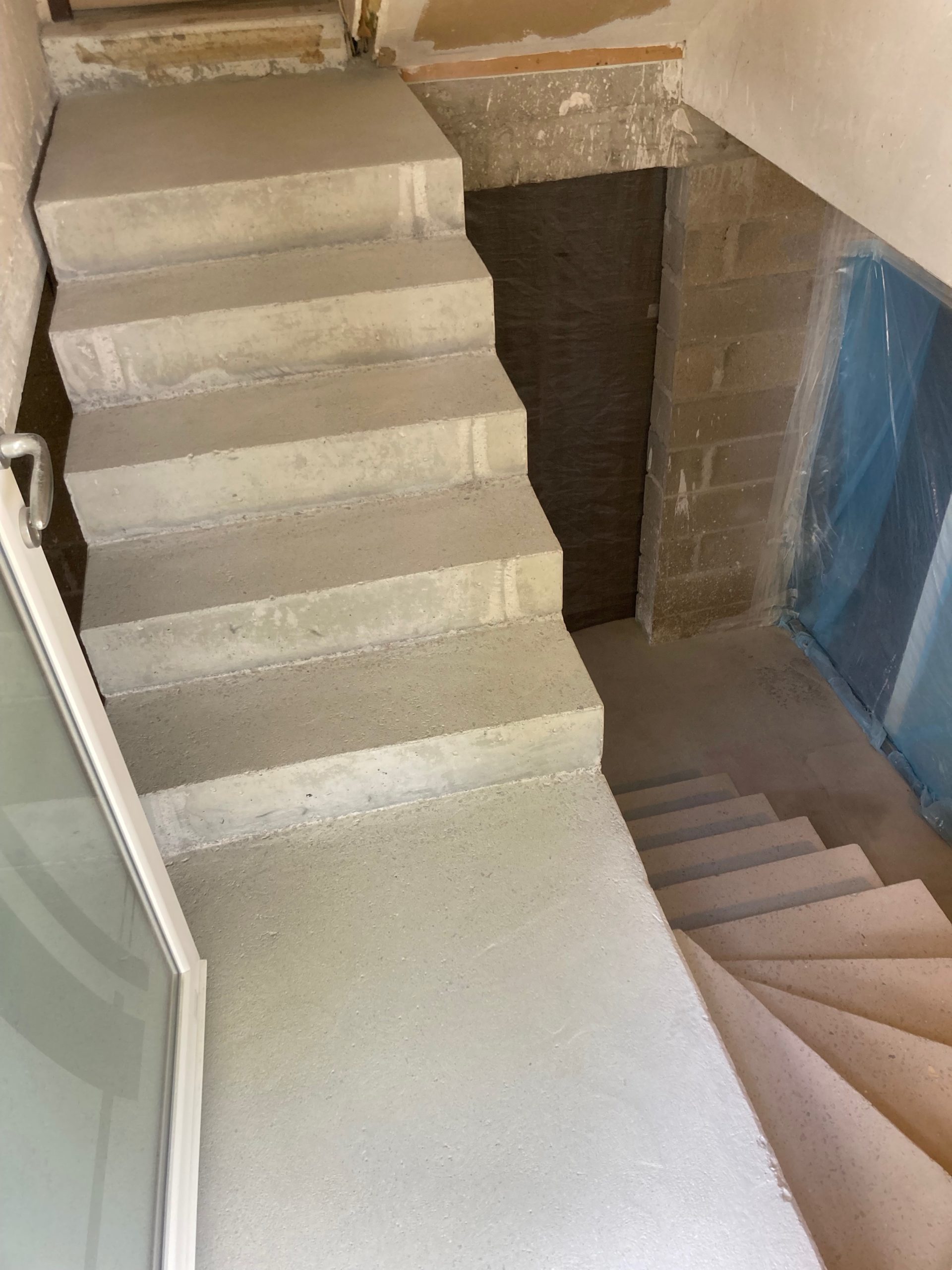 Escalier à paillasse principal un quart tournant en béton, situé au sous-sol d'une maison, en région Nouvelle-Aquitaine.