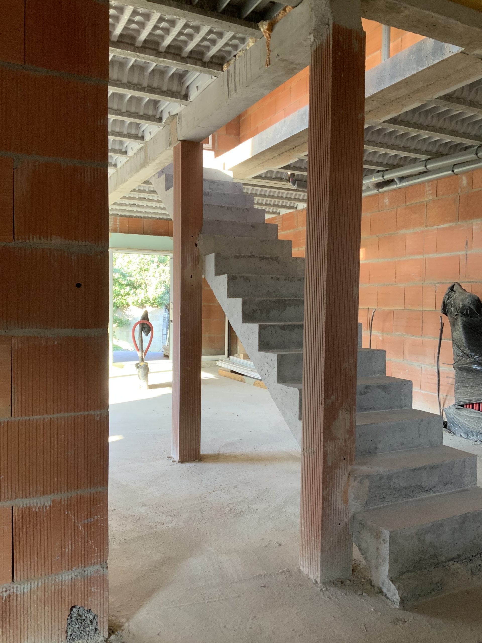 Escalier droit entre deux poteaux dans une villa en briques en cours de construction