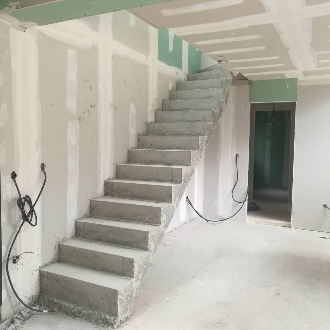 Montée d'un escalier béton à paillasse le long d'un mur, dans une maison individuelle à Evry, à proximité de Paris.